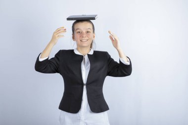 Genç ve güzel bir kız beyaz arka planda kafasında kitap tutuyor. Yüksek kalite fotoğraf