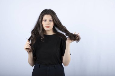 Siyah bluzlu esmer bir kızın beyaz duvardan kameraya baktığı görüntü. Yüksek kalite fotoğraf