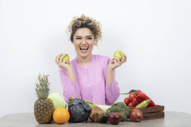 Güzel ev hanımının elinde taze elmalarla masada oturduğu bir fotoğraf. Yüksek kalite fotoğraf