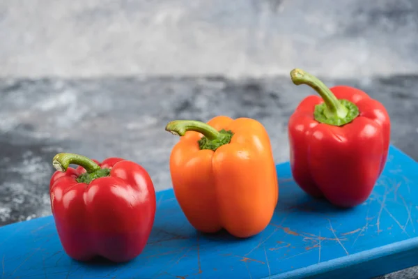 Tre Freschi Peperoni Biologici Colorati Sul Tagliere Blu Foto Alta — Foto Stock