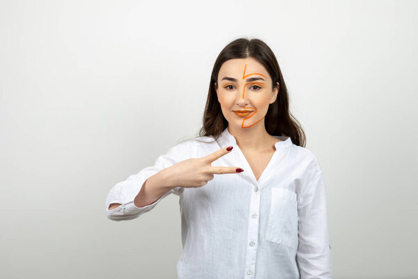 Image of young woman with painted face showing victory sign . High quality photo