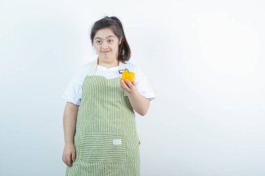 Kareli önlüğün içinde elinde sarı dolmalık biber tutan genç ve güzel bir kız. Yüksek kalite fotoğraf