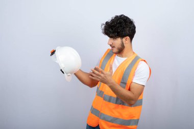 Beyaz duvarın üzerinden beyaz miğfere bakan üniformalı yakışıklı bir genç. Yüksek kalite fotoğraf