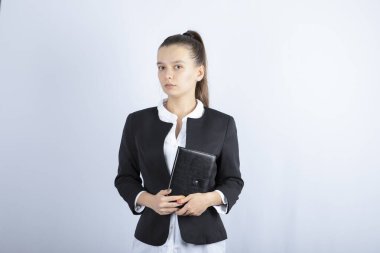 Beyaz arka planda duran defterli genç bayan öğretmenin portresi. Yüksek kalite fotoğraf