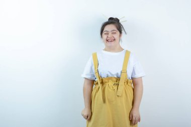 Beyaz duvarın karşısında duran ve gülümseyen genç, güzel kız modeli. Yüksek kalite fotoğraf