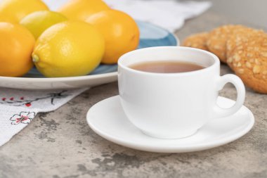 A white cup of hot tea with oatmeal cookies on a tablecloth . High quality photo