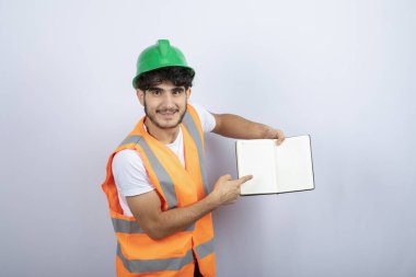 Yeşil şapkalı genç erkek mühendis beyaz arka planda notlar gösteriyor. Yüksek kalite fotoğraf