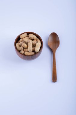 Ahşap kase dolusu soyulmamış fıstık ve beyaz arka planda kaşık. Yüksek kalite fotoğraf