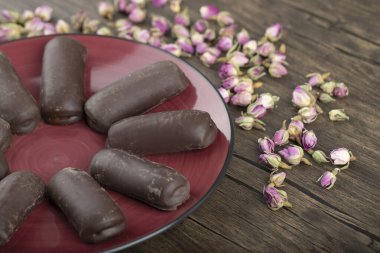 Kırmızı tabakta çikolatalı kekler ve ahşap arka planda güller. Yüksek kalite fotoğraf