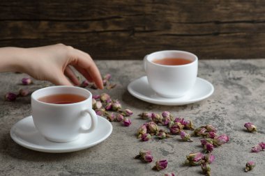 Kadın eli, mermer arka plandaki çay fincanına kurumuş çiçekler ekler. Yüksek kalite fotoğraf