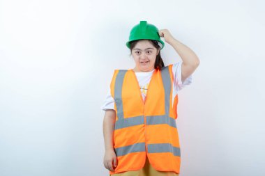 Beyaz duvarın üzerinde duran kasklı genç bayan inşaat işçisi. Yüksek kalite fotoğraf