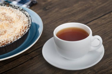 Hindistan cevizi parçalı tatlı turta ve ahşap zemin üzerinde bir fincan çay. Yüksek kalite fotoğraf