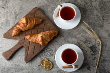 Taze ve lezzetli kruvasanlar ve iki fincan sıcak çay. Yüksek kalite fotoğraf