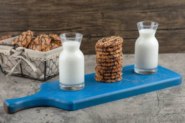 Mavi tahta bir tahtanın üzerinde yulaf ezmeli kurabiyeli iki bardak süt. Yüksek kalite fotoğraf