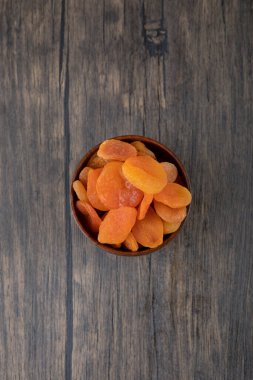 Ahşap bir masada sağlıklı kurutulmuş kayısı meyveleriyle dolu bir kase. Yüksek kalite fotoğraf