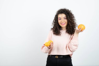 Güzel kıvırcık kız elinde taze portakal meyveleri tutuyor. Yüksek kalite fotoğraf