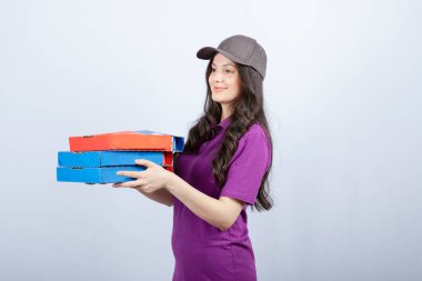 Mor üniformalı güzel teslimatçı pizza kutuları veriyor. Yüksek kalite fotoğraf