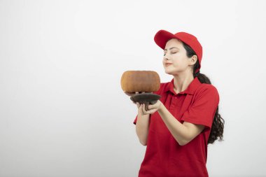 Kırmızı üniformalı esmer bir kadının elinde balkabağı resmi. Yüksek kalite fotoğraf