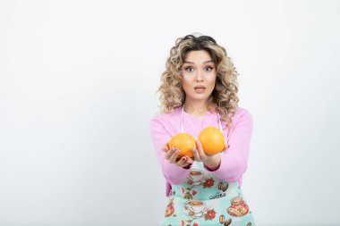 Portakallarla poz veren önlüklü genç kıvırcık kadın portresi. Yüksek kalite fotoğraf
