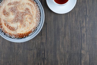 Tahta arka planda bir fincan çayla yuvarlak, lezzetli bir pasta. Yüksek kalite fotoğraf