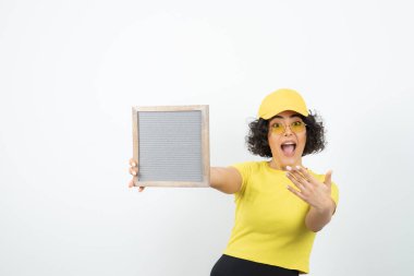 Beyaz arka planda poz veren pankartlı genç kadın. 