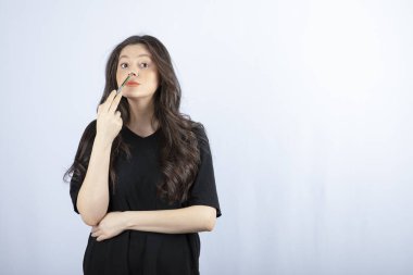 Güzel genç bir kadın burnuna kozmetik fırçasıyla fosforlu kalem koyuyor. Yüksek kalite fotoğraf