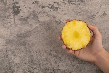 Taş zeminde ananasın yarısını tutan bir erkek. Yüksek kalite fotoğraf