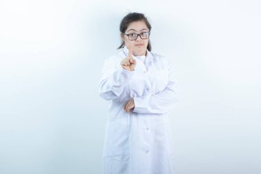 Doktor üniformalı genç bir kız ayakta ve parmağıyla işaret ediyor. Yüksek kalite fotoğraf