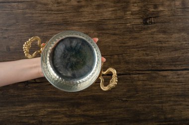 Ahşap arka planda boş metal bir tencereyi tutan kadın eli. Yüksek kalite fotoğraf