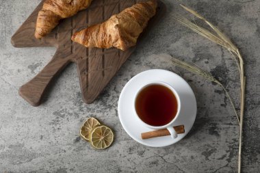 Taze ve lezzetli kruvasanlar ve bir fincan sıcak çay. Yüksek kalite fotoğraf