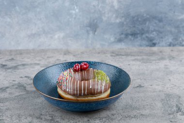 Çilekli çikolatalı donut ve mermer yüzeyine serpiştirilmiş mavi tabak. Yüksek kalite fotoğraf