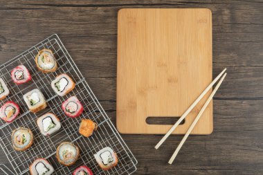 Ahşap zemin üzerinde çubuklar olan çeşitli suşi ruloları. Yüksek kalite fotoğraf