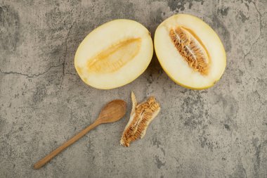 Ahşap kaşıkla mermer yüzeyde yarım lezzetli sarı kavunlar. Yüksek kalite fotoğraf
