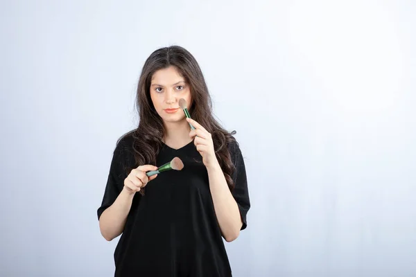 Imagem Jovem Modelo Bonito Aplicando Maquiagem Com Escova Fundo Branco — Fotografia de Stock