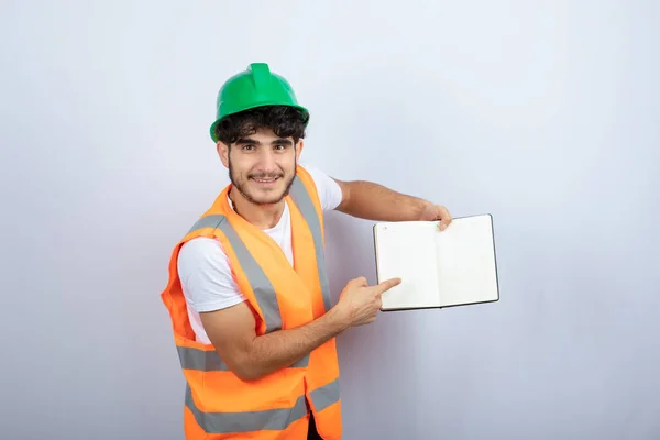 Joven Ingeniero Masculino Hardhat Verde Mostrando Notas Sobre Fondo Blanco — Foto de Stock