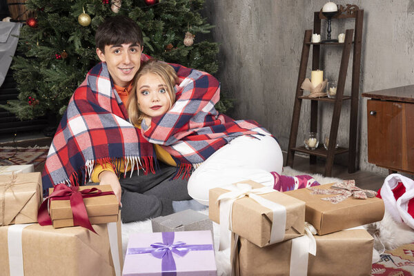 A beautiful young couple is wrapped in a warm blanket at home interior . High quality photo