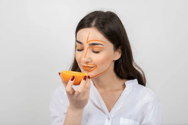 Gambar Wanita Muda Dengan Wajah Dicat Memegang Setengah Oranye Foto — Stok Foto