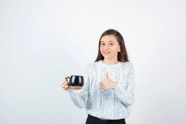 Νεαρή Γυναίκα Κρατάει Ένα Φλιτζάνι Ζεστό Καφέ Και Δείχνει Τον — Φωτογραφία Αρχείου