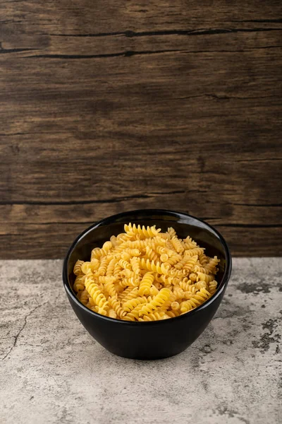 Black Bowl Raw Fusilli Pasta Stone Background High Quality Photo — Stock Photo, Image