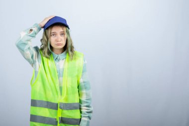 Üniformalı genç bayan mimar beyaz duvarın arkasında dalgın dalgın duruyor. Yüksek kalite fotoğraf