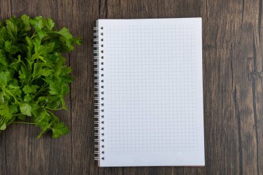 Sağlıklı yeşil maydanoz yaprakları ve tahta arka planda boş defter. Yüksek kalite fotoğraf