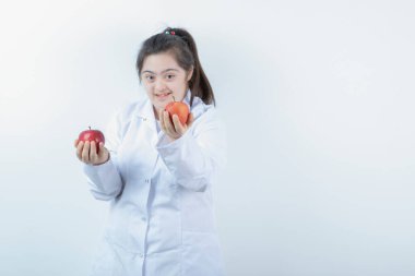 Doktor üniformalı genç bir kız elinde kırmızı elma meyveleri tutuyor. Yüksek kalite fotoğraf