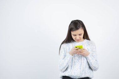 Beyaz arka planda akıllı telefon kullanan genç bir kız. Yüksek kalite fotoğraf