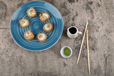 Mavi bir tabak soya soslu tempura rulo ve taş yüzeyinde wasabi. Yüksek kalite fotoğraf