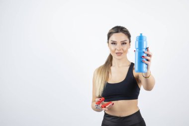 Siyah elbiseli sarışın kadın ayakta duruyor ve elinde şişesi genişletilmiş su tutuyor. Yüksek kalite fotoğraf