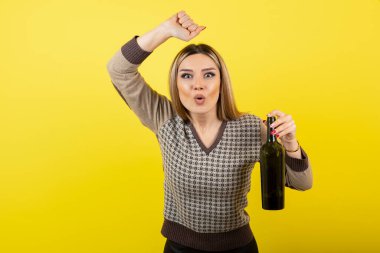 Elinde şarap şişesi olan ve ayakta duran genç bir kadın resmi. Yüksek kalite fotoğraf