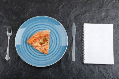 Mavi tabak lezzetli pizza dilimi ve siyah arka planda not defteri. Yüksek kalite fotoğraf