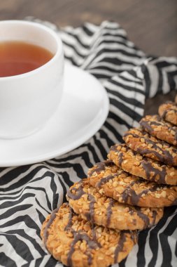 Tahta bir masaya yerleştirilmiş beyaz fincanlı çok tahıllı kurabiyeler. Yüksek kalite fotoğraf