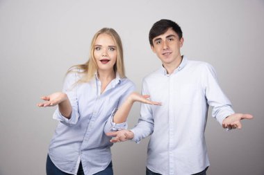 Genç bir çiftin, avuçlarını açık tutarak omuz silkerken çekilmiş fotoğrafı. Yüksek kalite fotoğraf