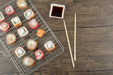 Çeşitli suşi çeşitleri, yemek çubukları ve soya sosuyla ahşap arka planda. Yüksek kalite fotoğraf